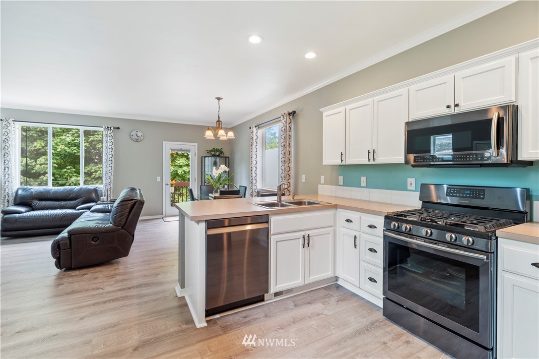 1162 Edmonds Place Northeast Renton, WA 98056 - Photo 13 of 25 a kitchen with stainless steel appliances granite countertop a stove top oven a sink dishwasher a dining table and chairs with wooden floor