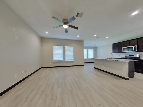 a view of an empty room with a window and wooden floor