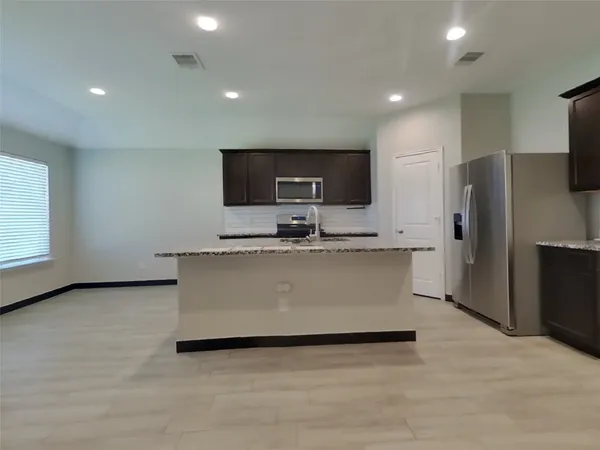 a view of kitchen with stainless steel appliances a refrigerator a microwave a sink and a counter top space
