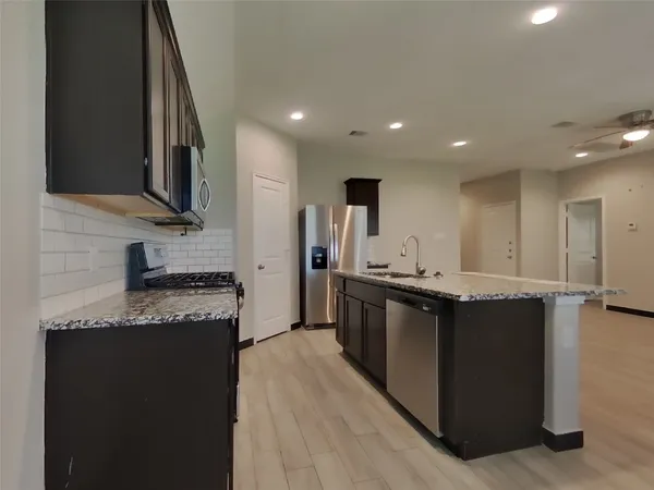 a kitchen with stainless steel appliances granite countertop a stove a sink and a refrigerator