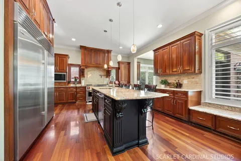 a kitchen with stainless steel appliances granite countertop a table chairs and a refrigerator