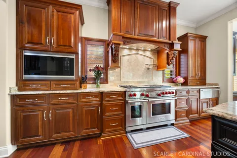 a large kitchen with stainless steel appliances granite countertop a stove and a view of living room