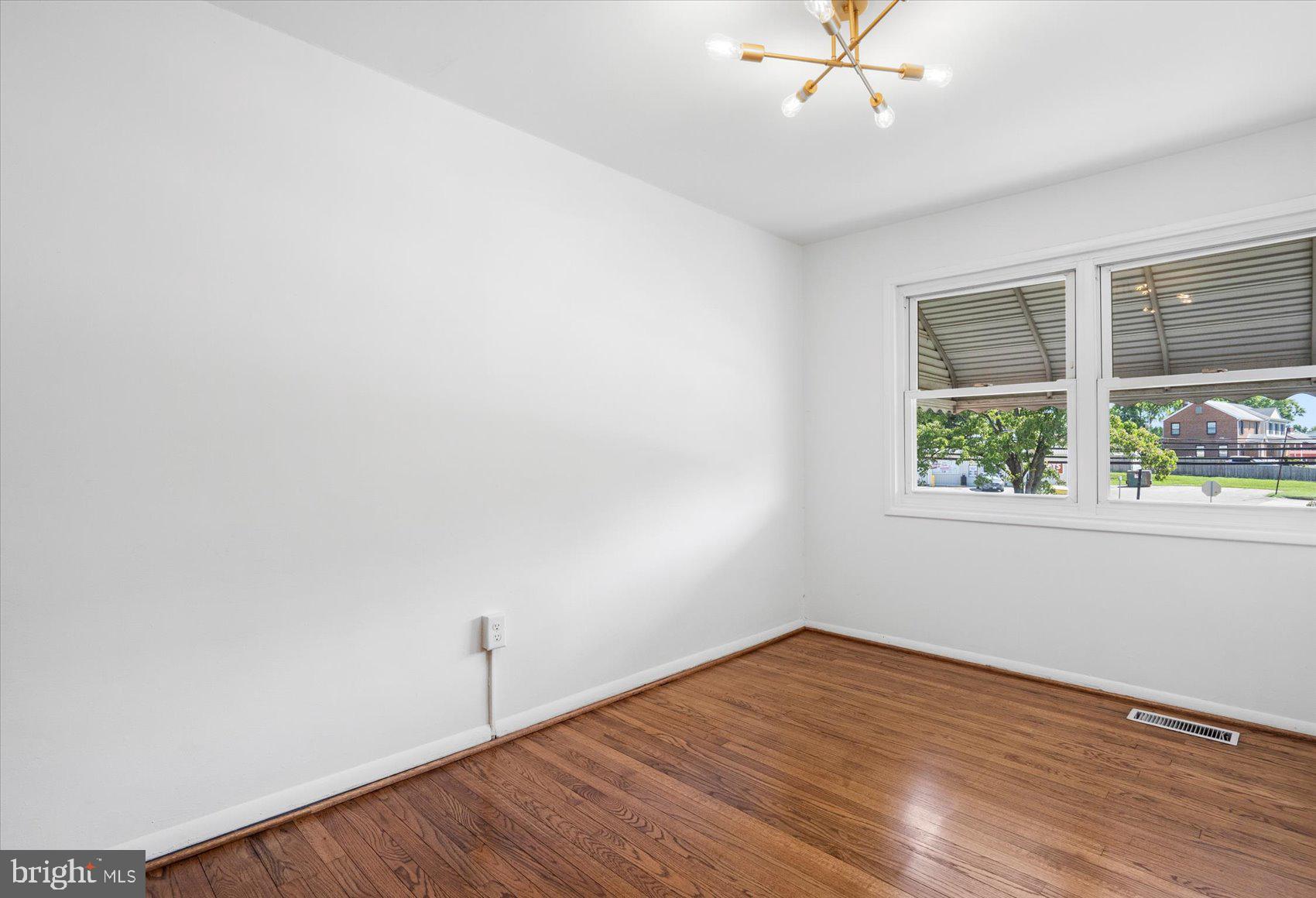 4430 Annapolis Road Halethorpe, MD 21227 - Photo 17 of 23 an empty room with wooden floor chandelier fan and windows
