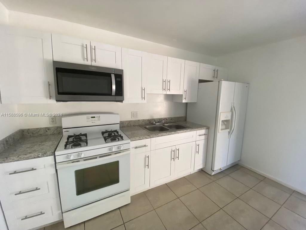 641 Silver Beach Road Riviera Beach, FL 33403 - Photo 3 of 13 a kitchen with granite countertop white cabinets and white appliances