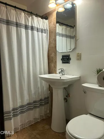 a bathroom with a sink a toilet and shower curtain