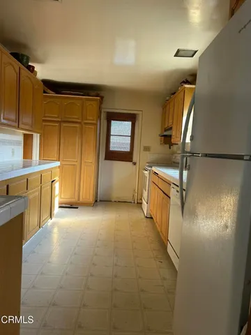 a view of a kitchen with a sink a refrigerator and cabinets