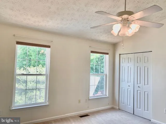 an empty room with windows and fan