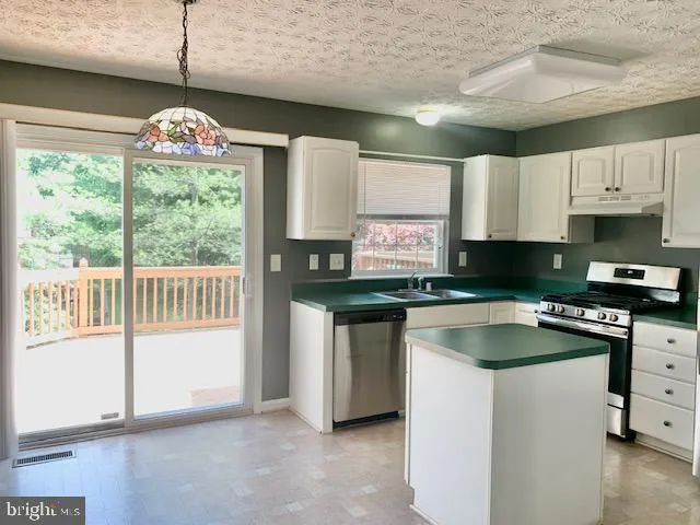 a kitchen with granite countertop a sink a counter top space and stainless steel appliances