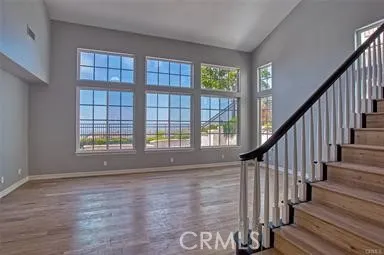 a view of an empty room with wooden floor and fan