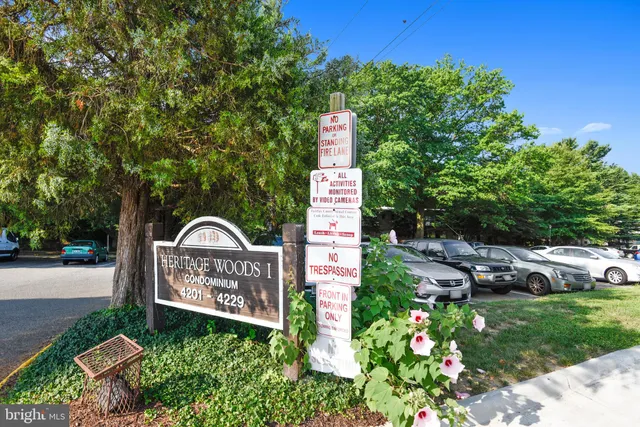 a sign that is sitting in front of a house with a big yard