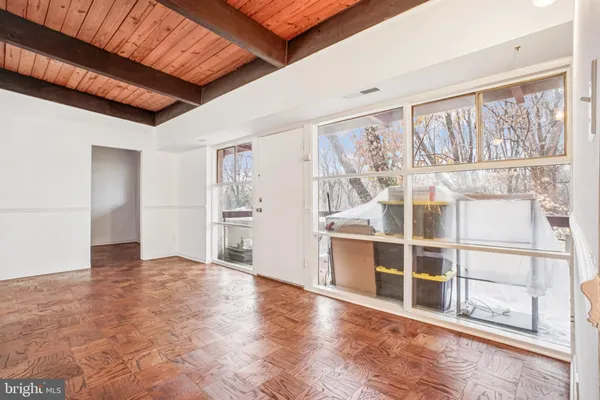 a view of an empty room with wooden floor and windows