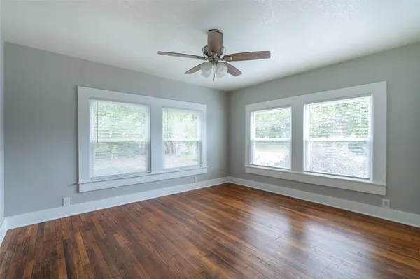 a view of an empty room with wooden floor and a window