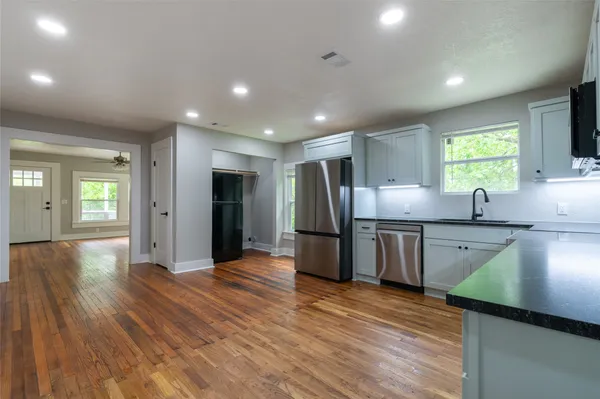a kitchen with stainless steel appliances granite countertop a lot of counter space and wooden floors