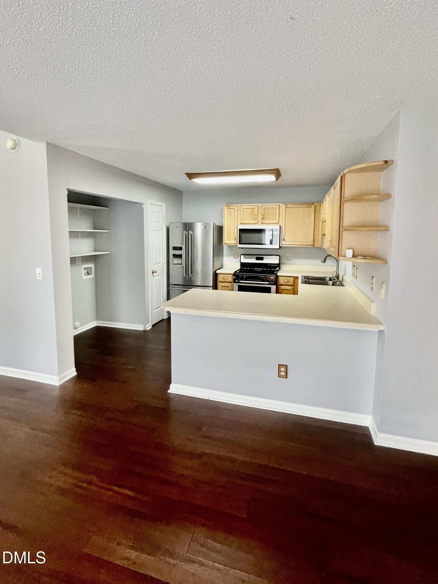 5428 Roan Mountain Place Raleigh, NC 27613 - Photo 5 of 22 This kitchen is tucked in across from the dining area and double doors leading to the patio. Washer/dryer location is to the left in this image. SS refrigerator conveys.