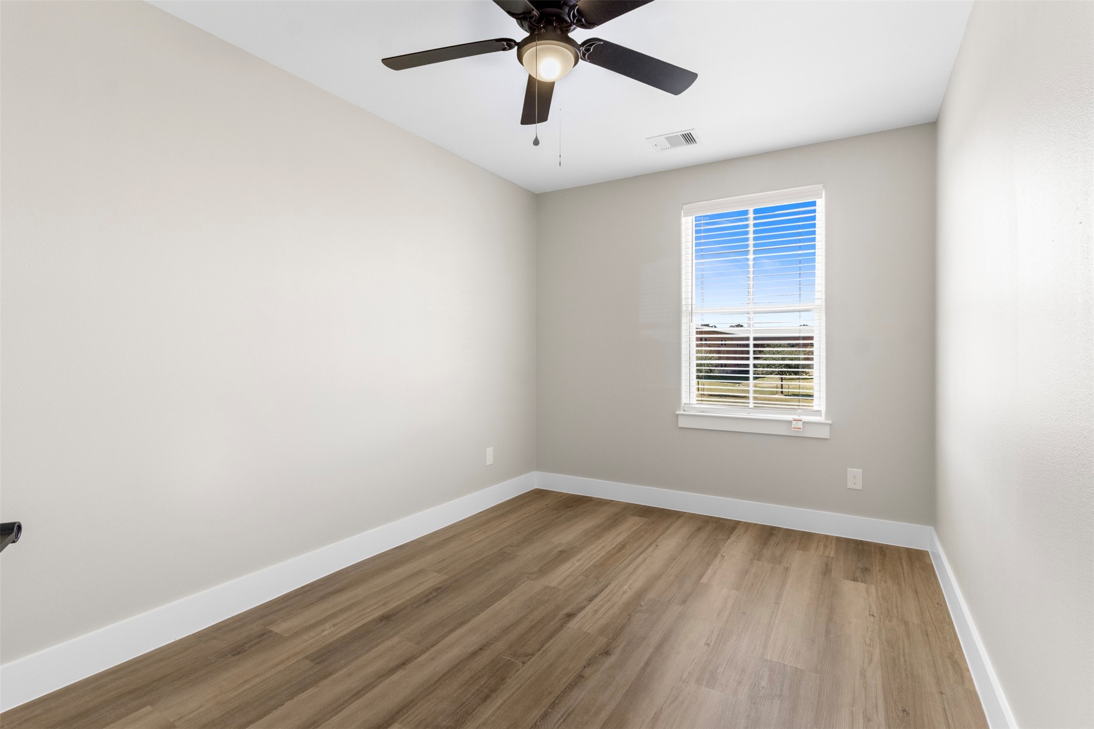 3150 South Cleveland Street Dayton, TX 77535 - Photo 13 of 24 an empty room with wooden floor fan and windows