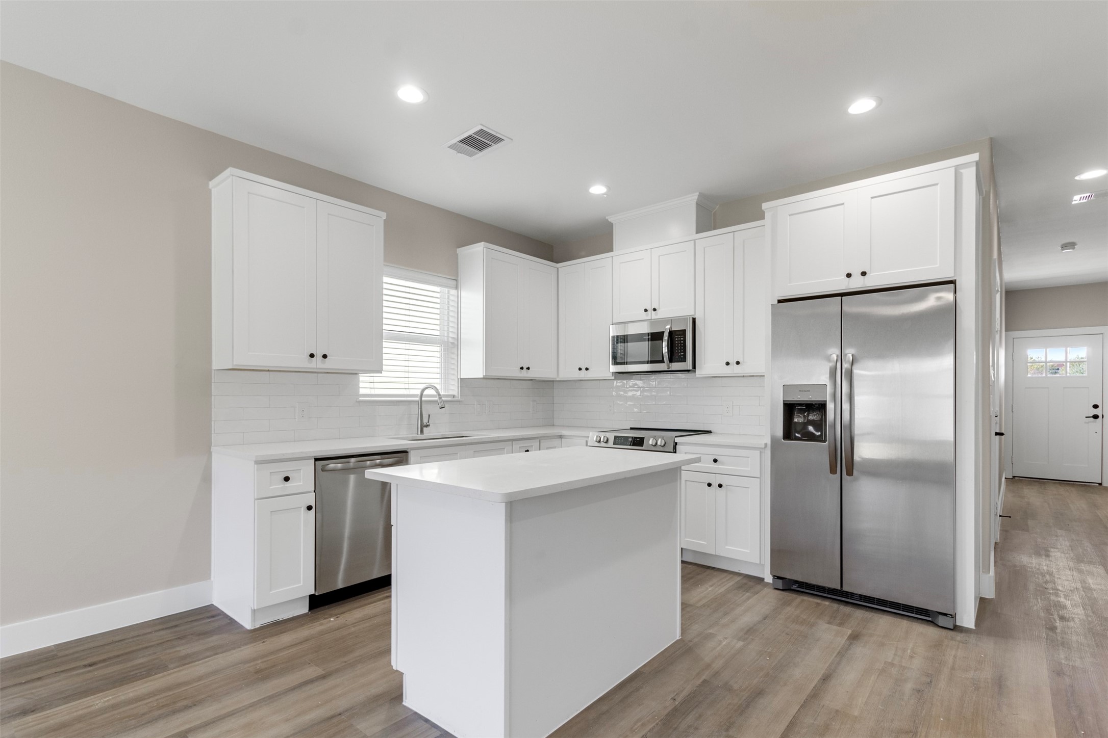 3150 South Cleveland Street Dayton, TX 77535 - Photo 3 of 24 a kitchen with stainless steel appliances granite countertop a refrigerator a sink a stove and white cabinets with wooden floor