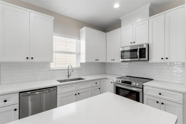 a kitchen with white cabinets and stainless steel appliances