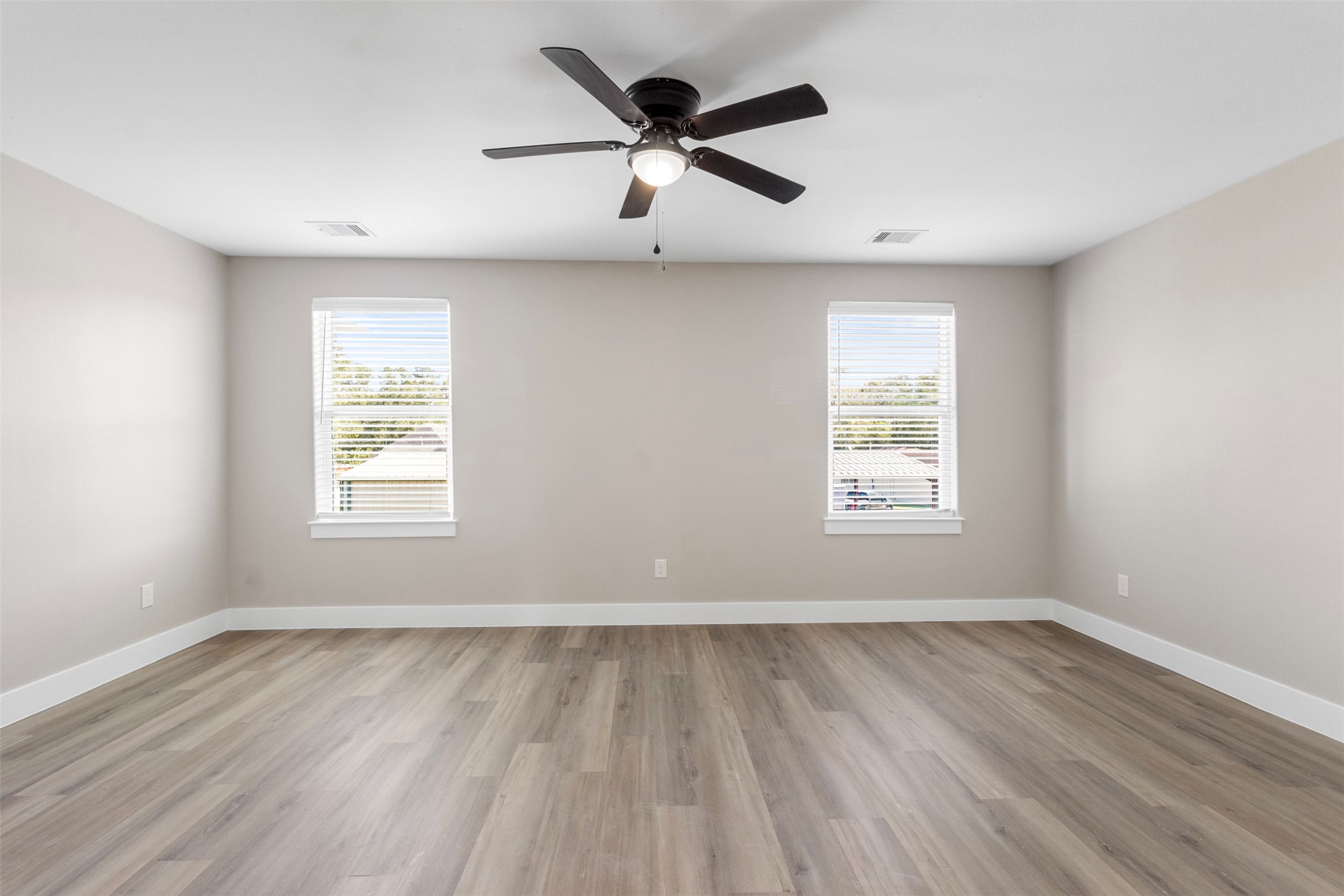 3150 South Cleveland Street Dayton, TX 77535 - Photo 8 of 24 an empty room with wooden floor ceiling fan and windows