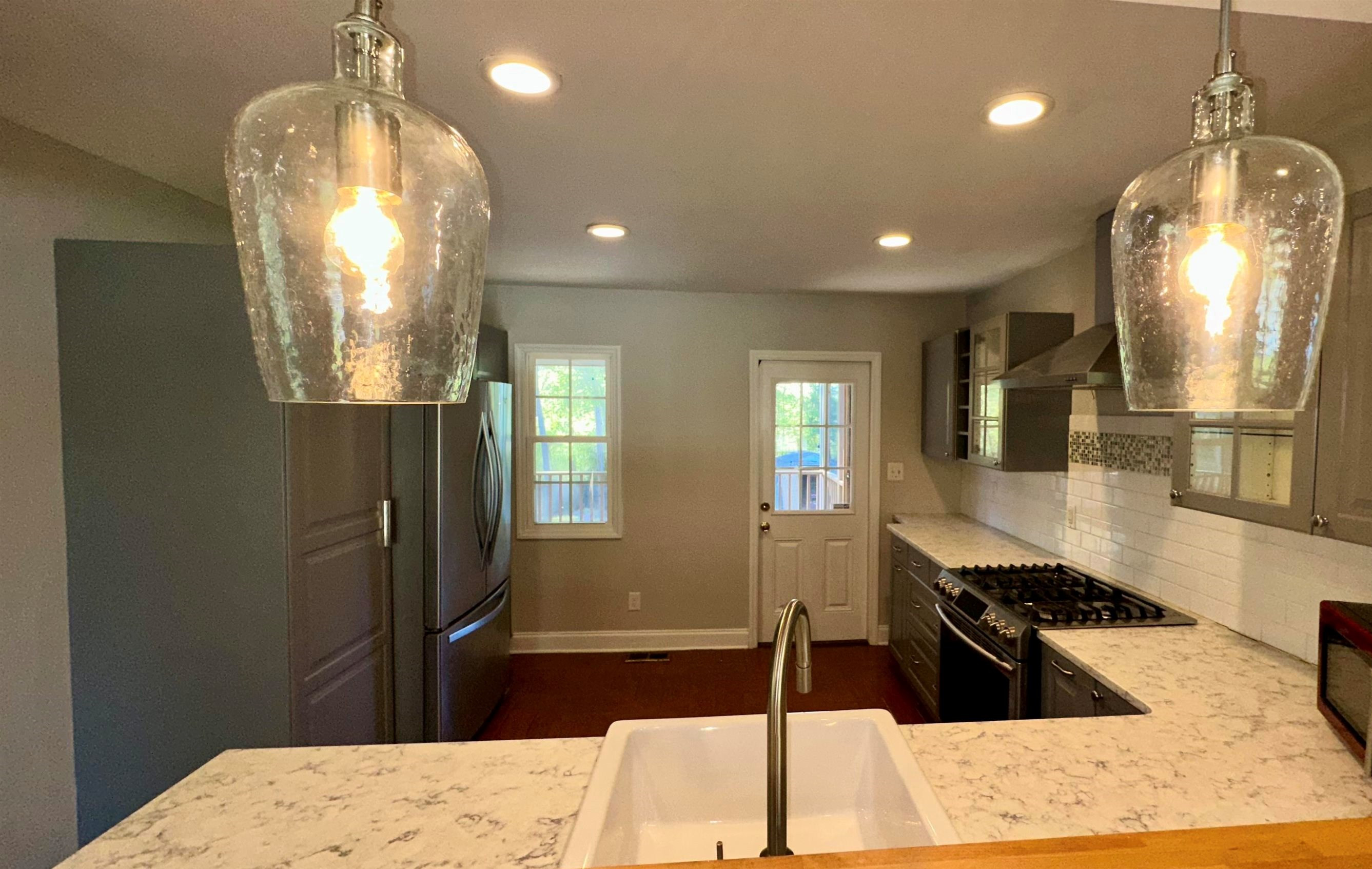 1113 Marlborough Road Raleigh, NC 27610 - Photo 4 of 28 a kitchen with stainless steel appliances kitchen island granite countertop a refrigerator a stove and a sink with wooden floor