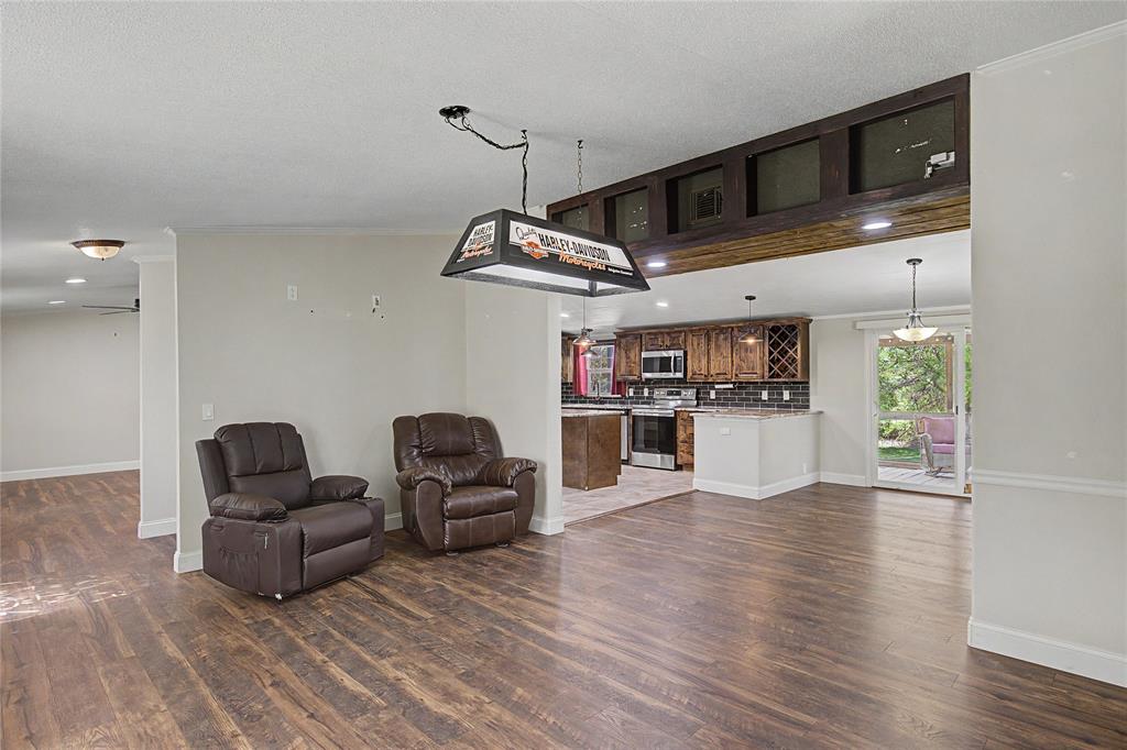 1701 Central Road Weatherford, TX 76088 - Photo 14 of 40 Living area or formal dining room featuring ceiling fan, crown molding, dark wood finished floors, and recessed lighting with a view of the breakfast/dining room and kitchen.