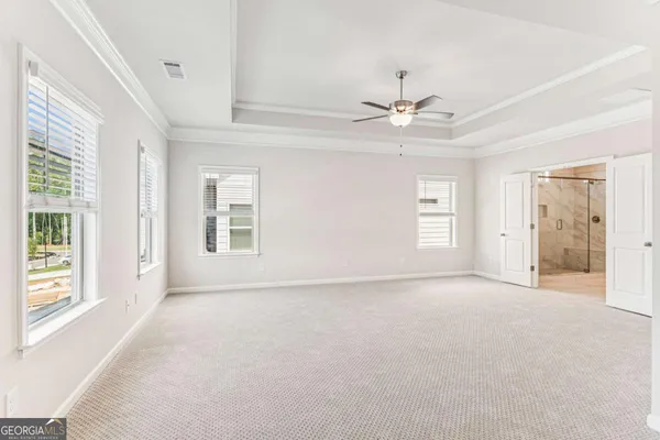 an empty room with chandelier fan and windows
