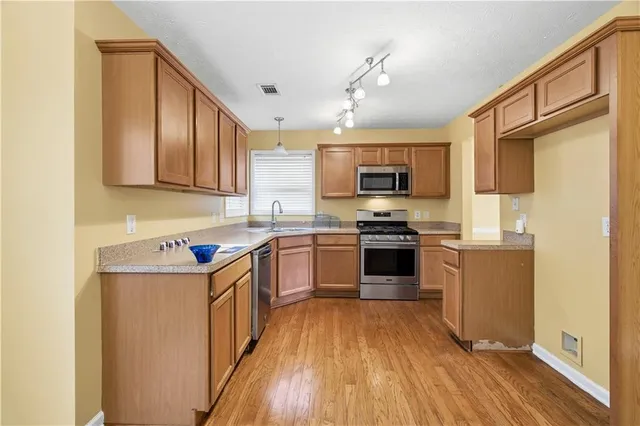 a kitchen with granite countertop a stove top oven a sink dishwasher and a refrigerator with wooden floor