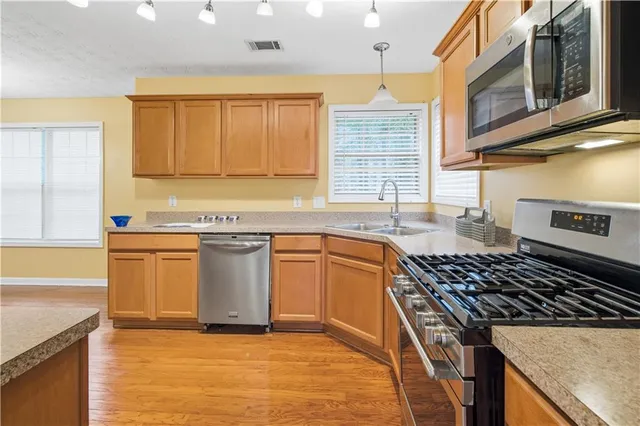 a kitchen with stainless steel appliances granite countertop a stove a sink and a microwave