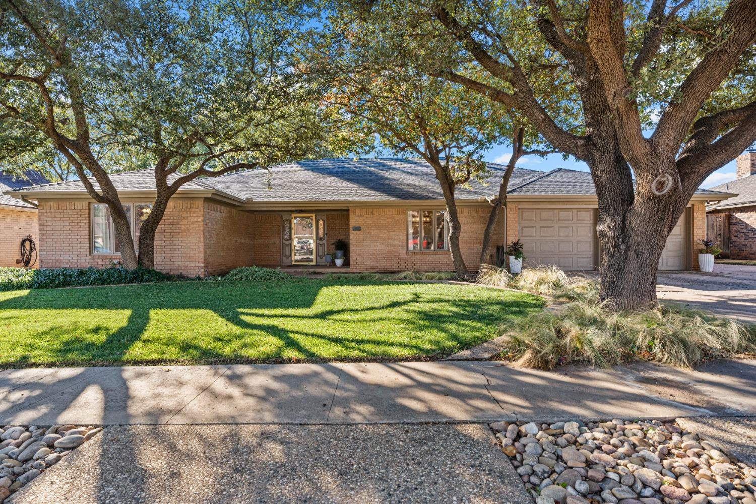 a front view of a house with a yard and an trees