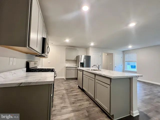 a view of a refrigerator in kitchen and an empty room