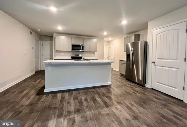a kitchen with kitchen island a refrigerator and a stove top oven