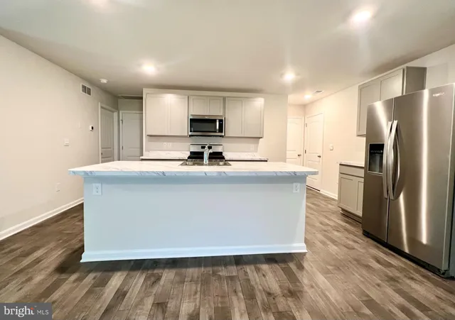 a kitchen with kitchen island a sink stainless steel appliances and white cabinets