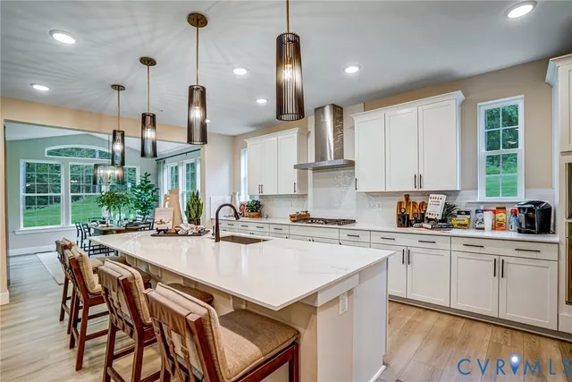 a kitchen with a stove a sink a kitchen island with chairs and wooden cabinets