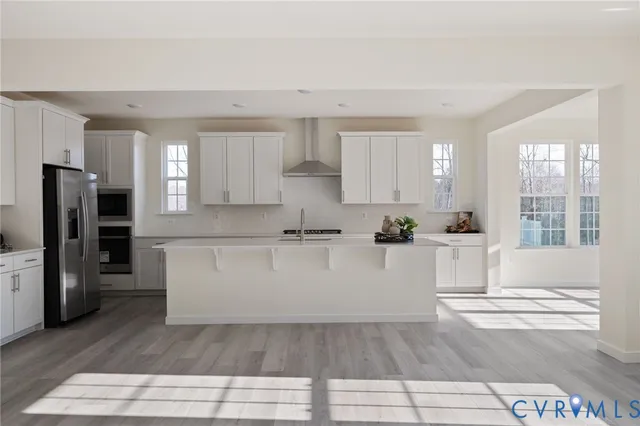a white kitchen with wooden floor and stainless steel appliances