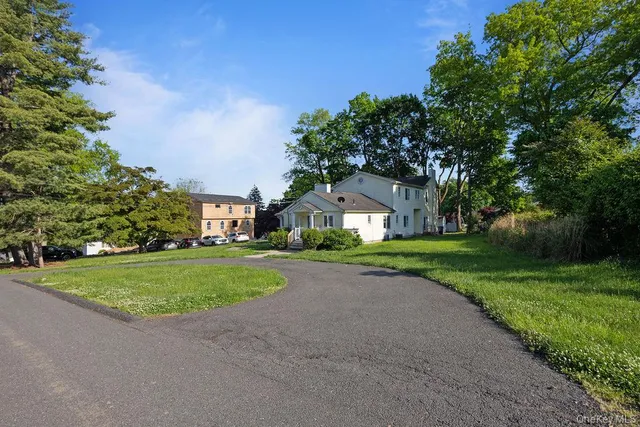a view of a big house with a big yard and large trees