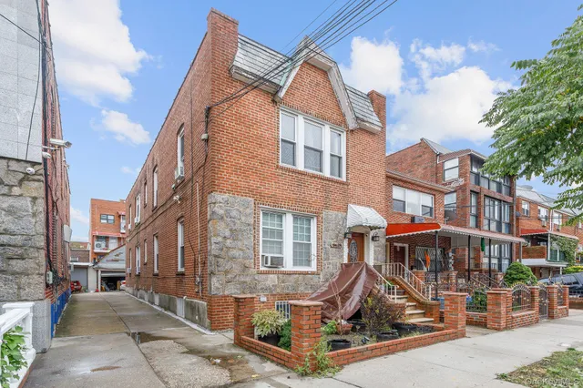 a view of a brick house with many windows next to a yard