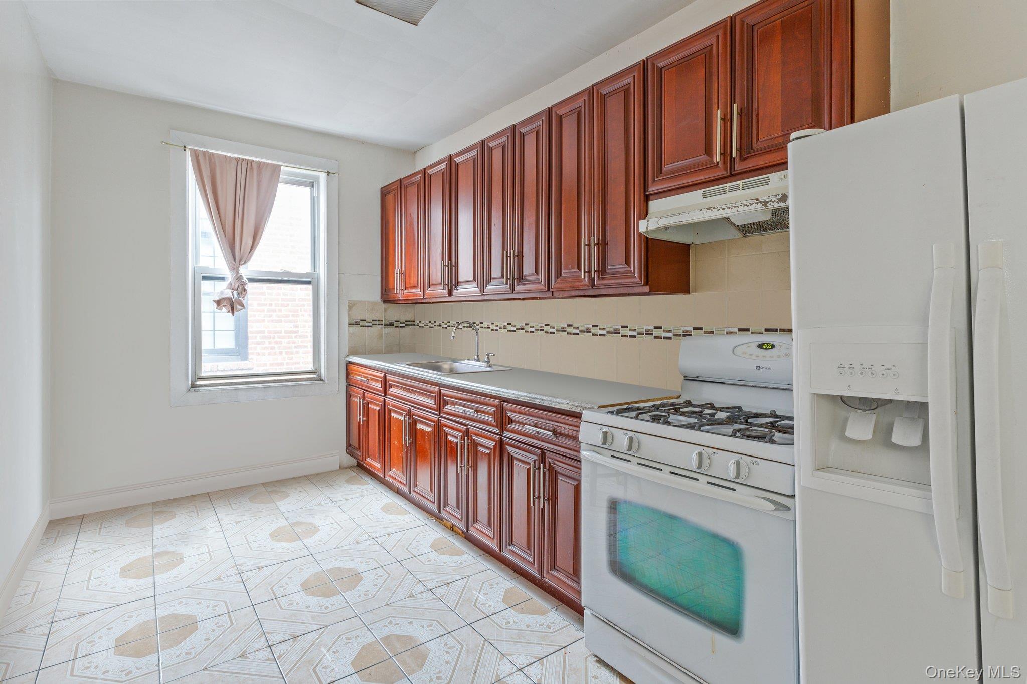 34-29 58th Street Queens, NY 11377 - Photo 17 of 23 a kitchen with wooden cabinets and a stove top oven