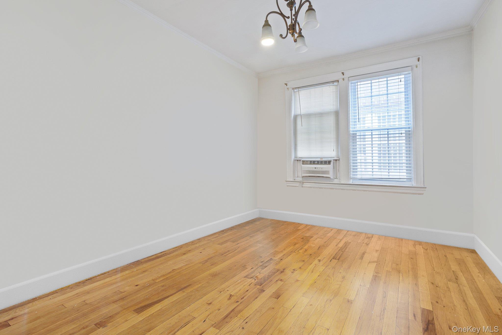 34-29 58th Street Queens, NY 11377 - Photo 19 of 23 a view of an empty room with wooden floor and a window