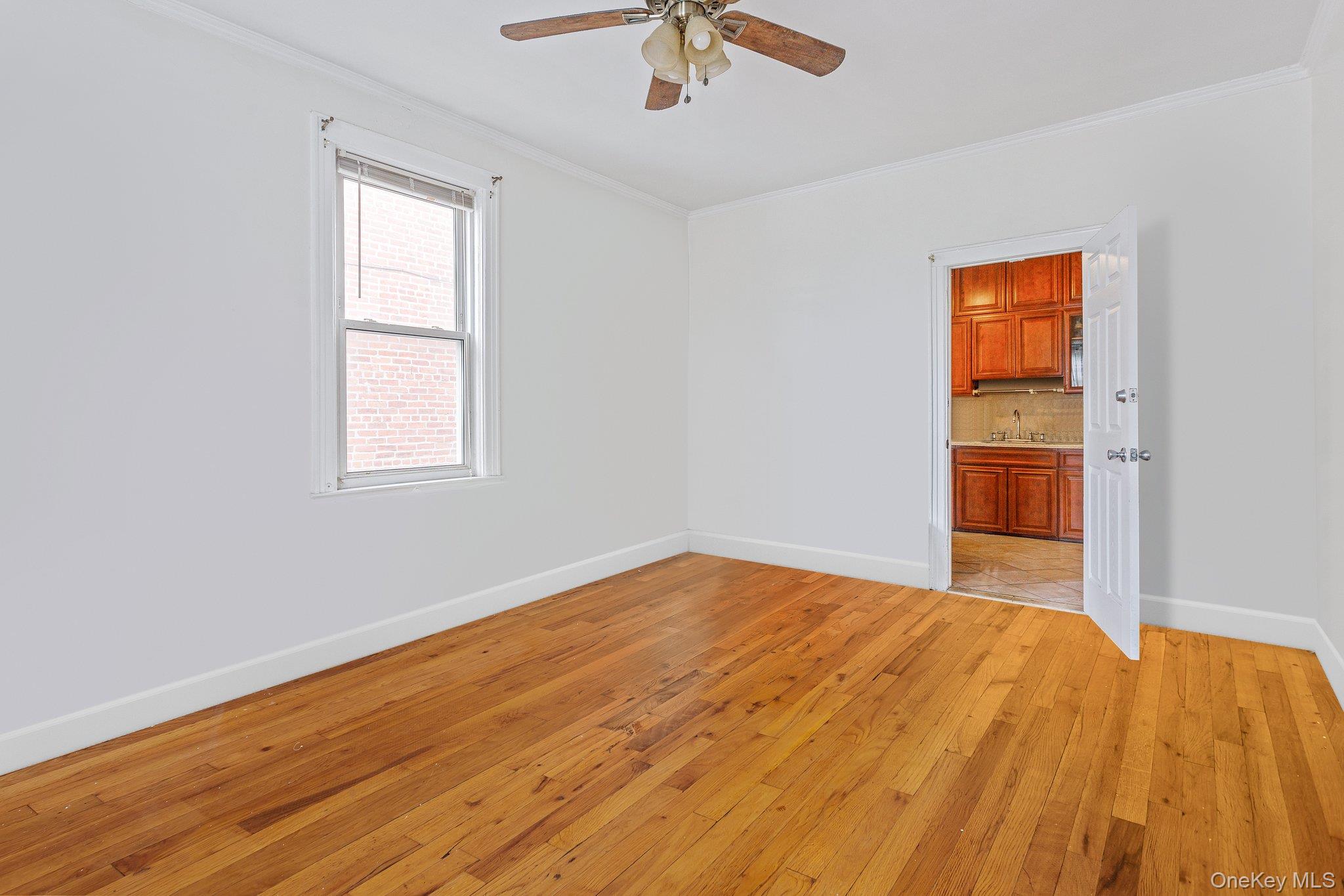 34-29 58th Street Queens, NY 11377 - Photo 22 of 23 a view of empty room with wooden floor and fan