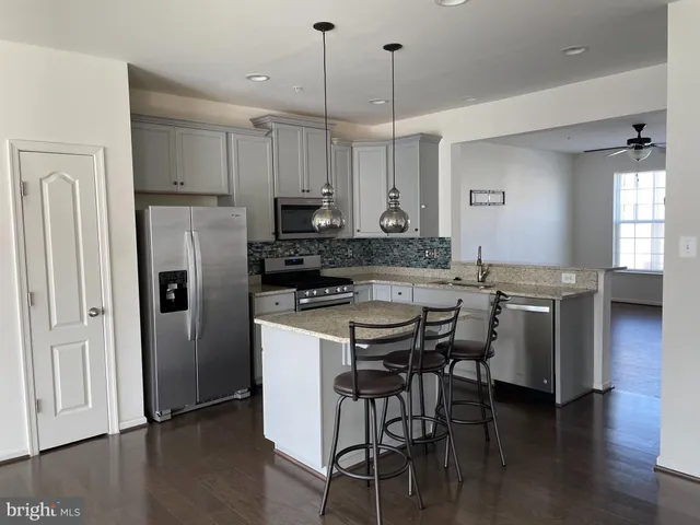 a kitchen with stainless steel appliances kitchen island a table chairs refrigerator and microwave