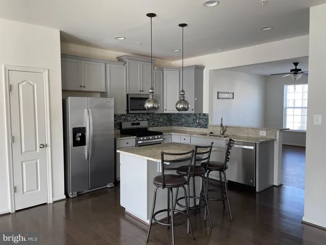 a kitchen with stainless steel appliances kitchen island a refrigerator a stove a sink and chairs
