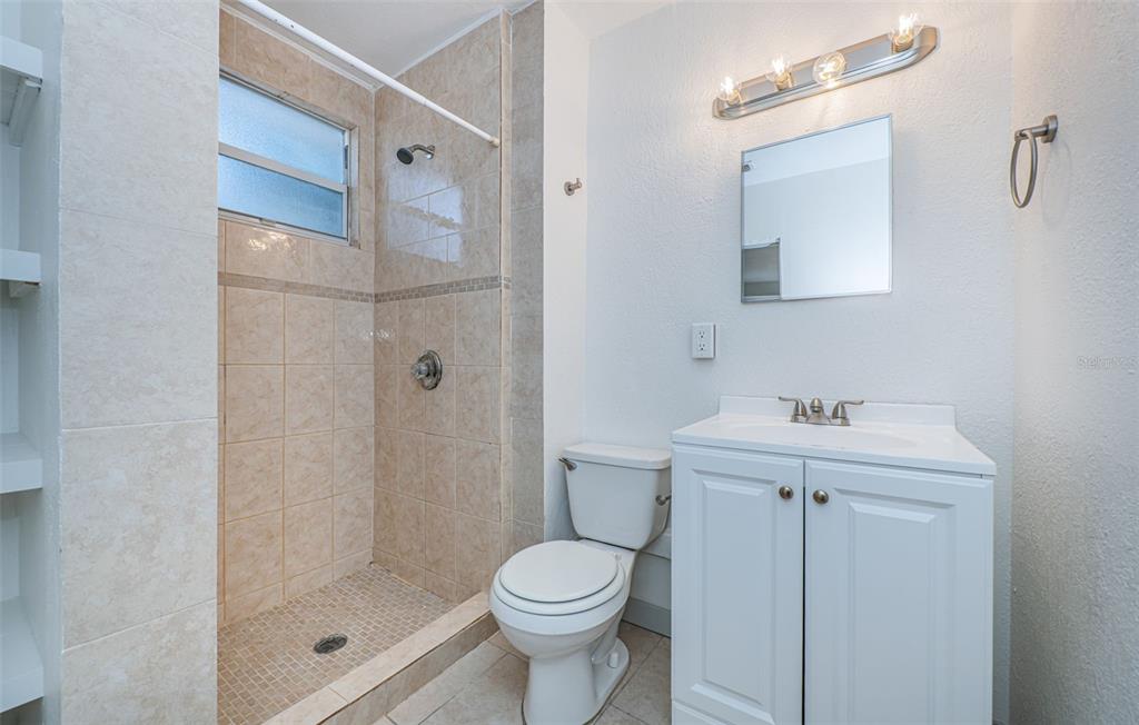 6027 Illinois Avenue New Port Richey, FL 34653 - Photo 13 of 30 a bathroom with a shower sink vanity and toilet