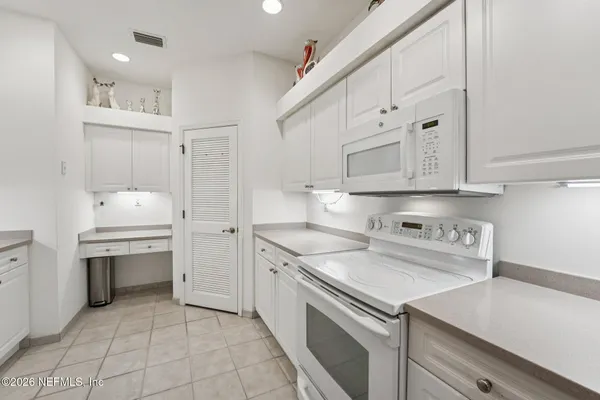a kitchen with white cabinets and refrigerator