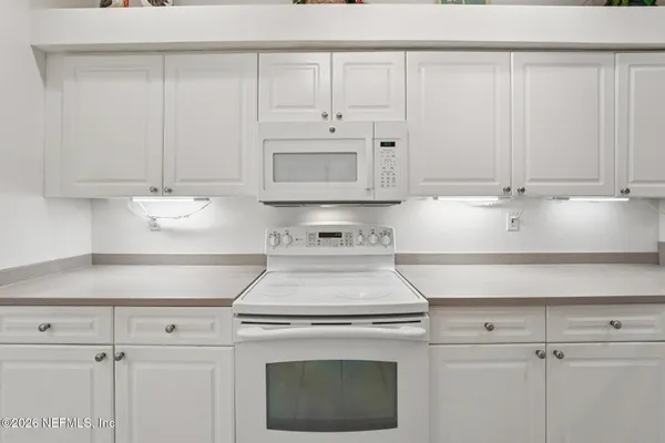 a kitchen with white cabinets and white appliances