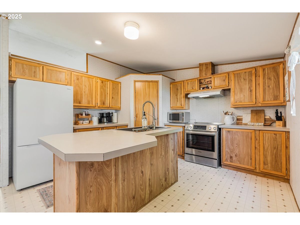 78527 Point Adams Road Clatskanie, OR 97016 - Photo 18 of 46 a kitchen with kitchen island granite countertop a stove top oven a sink dishwasher and white cabinets with wooden floor