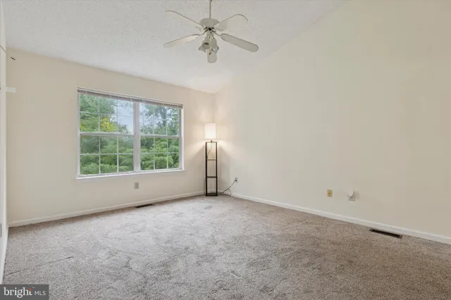 an empty room with a window and a fan