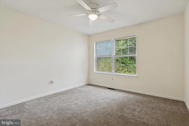 an empty room with a window and a fan