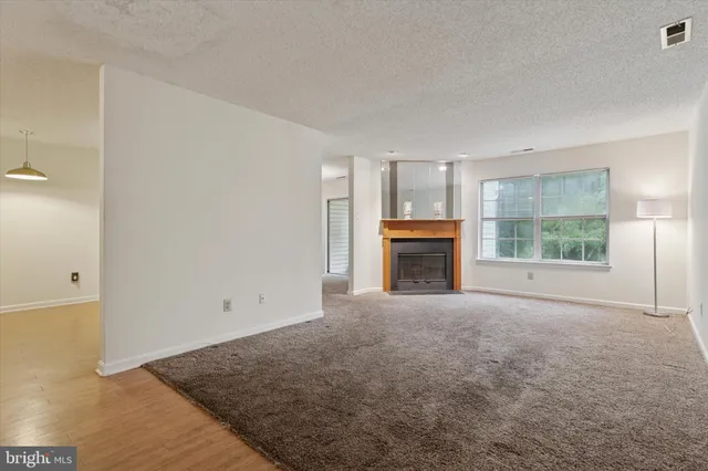 an empty room with windows and fireplace