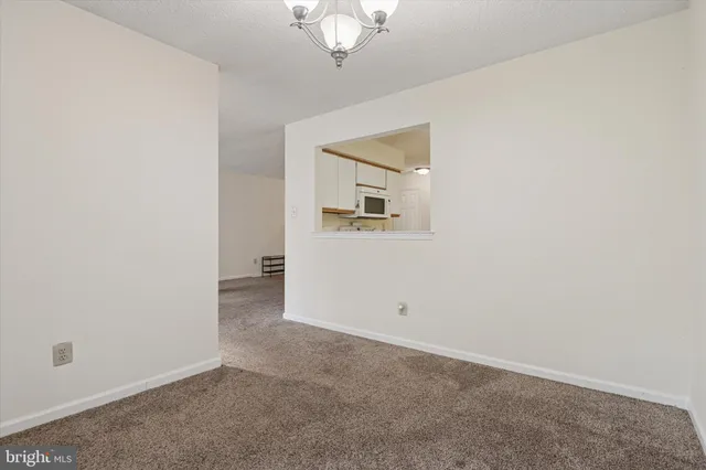 an empty room with a chandelier fan and windows
