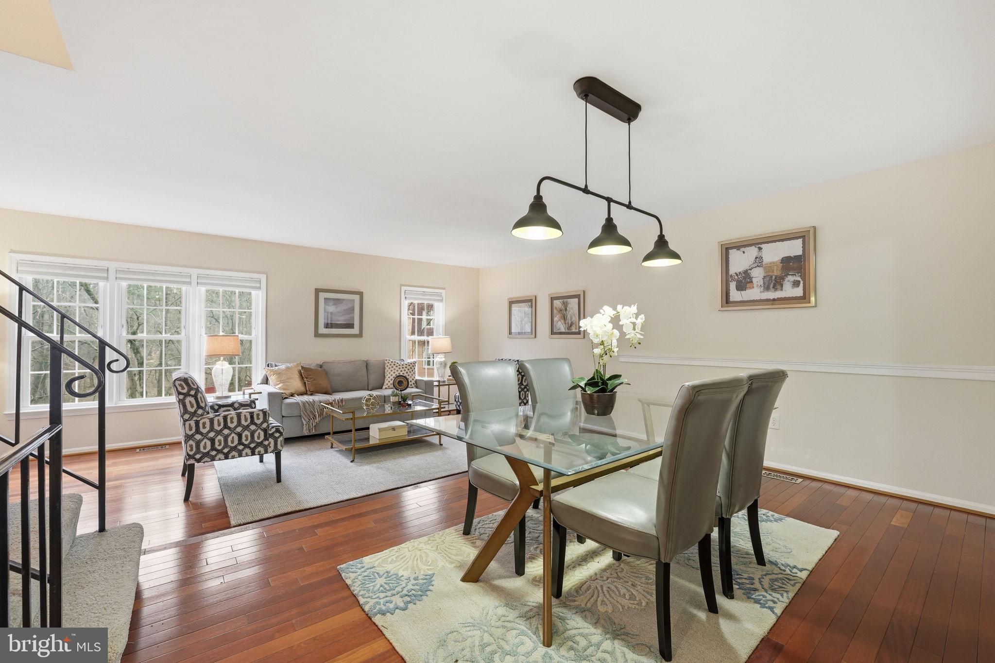 8967 Omega Court Springfield, VA 22152 - Photo 2 of 31 a dining room with furniture wooden floor a rug and a chandelier