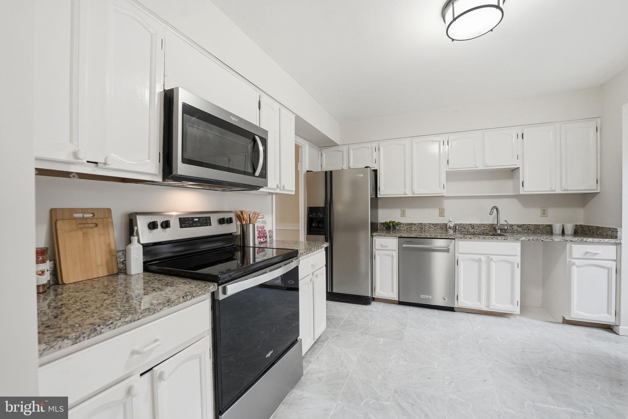 8967 Omega Court Springfield, VA 22152 - Photo 7 of 31 a kitchen with refrigerator a microwave a stove and cabinets